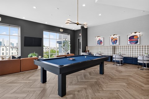 A pool table is in the middle of a room with a couch and a television.