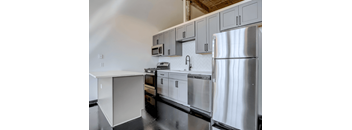 Historic Loft Style Studio in Cabbagetown With A Modern kitchen with white cabinets and stainless steel appliances