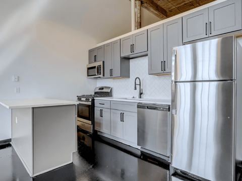 Historic Loft Style Studio in Cabbagetown With A Modern kitchen with white cabinets and stainless steel appliances