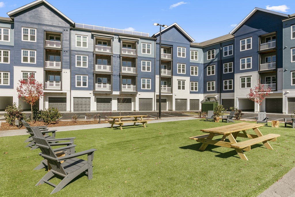 an outdoor area with picnic tables in front of an apartment building