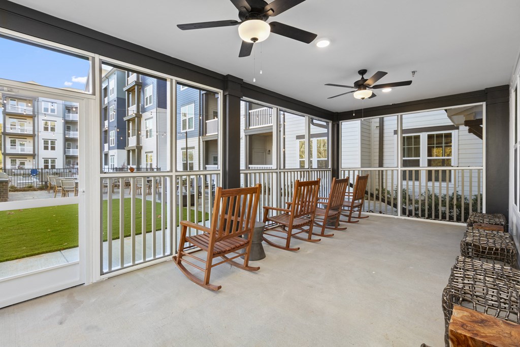 a covered patio with rocking chairs and a ceiling fan
