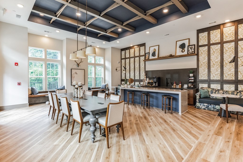 a dining room with a table and chairs in front of a kitchen with a bar