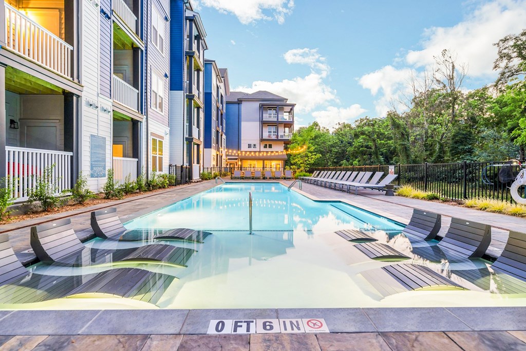 a swimming pool with lounge chairs in front of apartment buildings