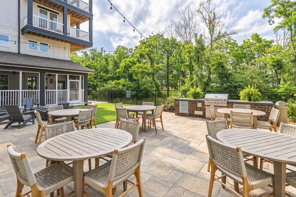 a patio with tables and chairs and a grill