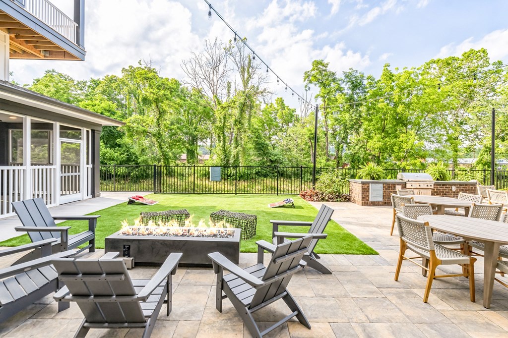 a patio with chairs and tables and a fire pit