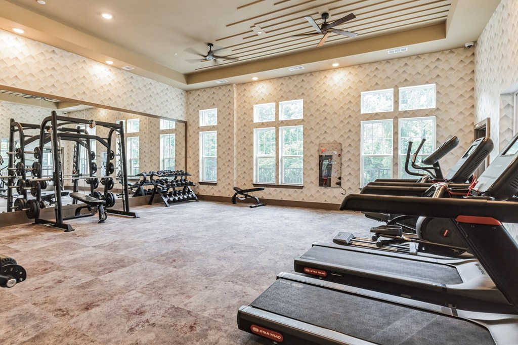 the gym has treadmills and other exercise equipment and windows