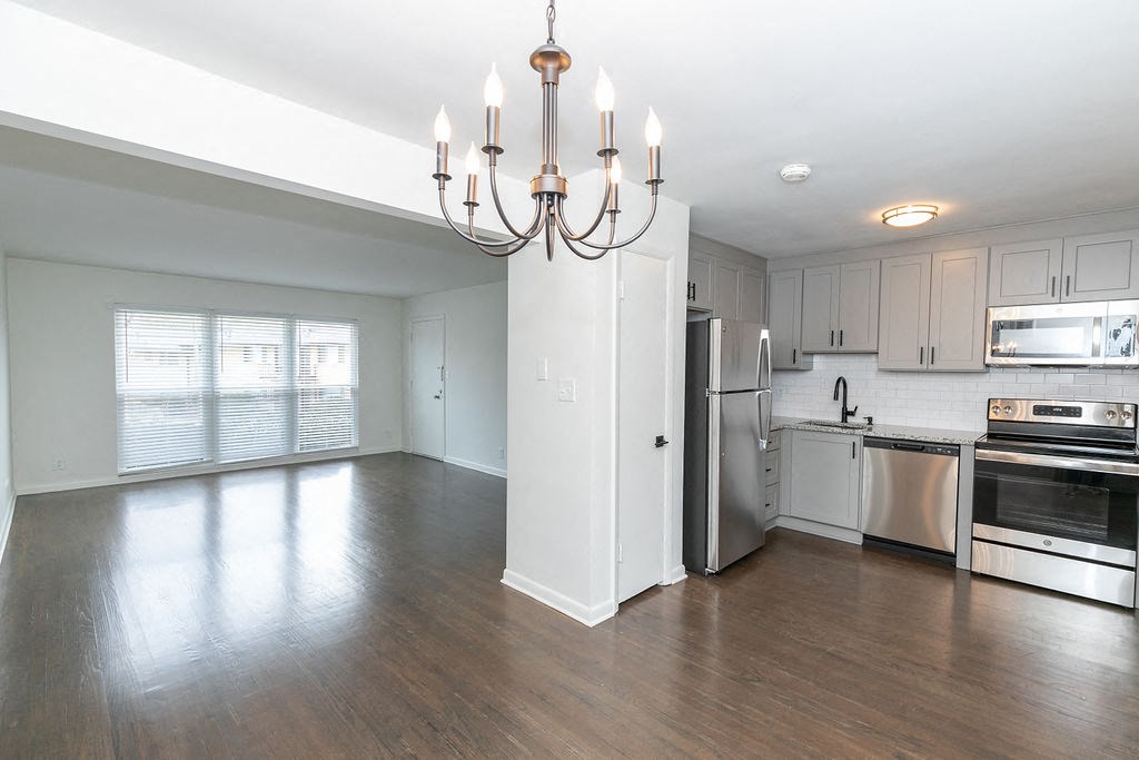 a kitchen and living room with white walls and wood floors