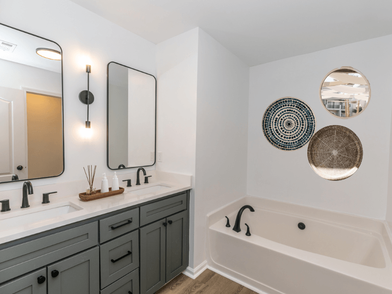 a bathroom with two sinks and a tub and two mirrors