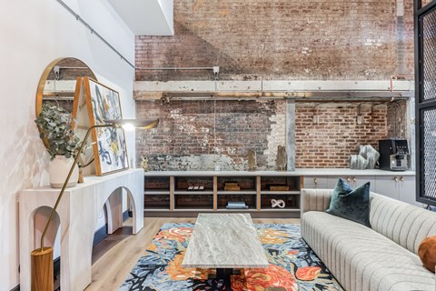 a living room with a white couch and a exposed brick wall