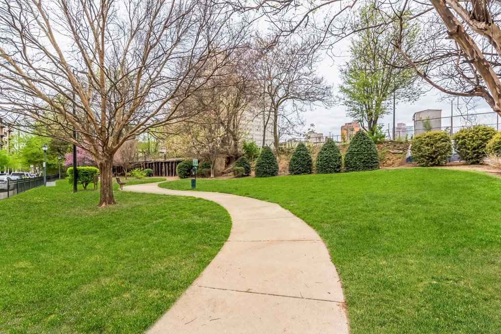 a sidewalk running through a park with grass and trees