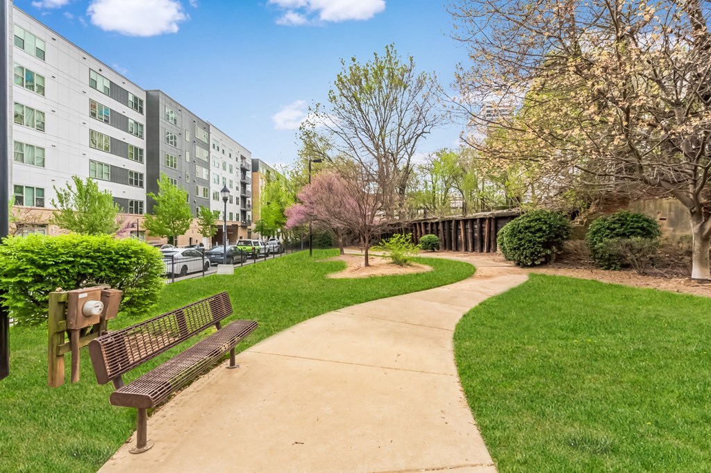 a park with benches and green grass and an apartment building
