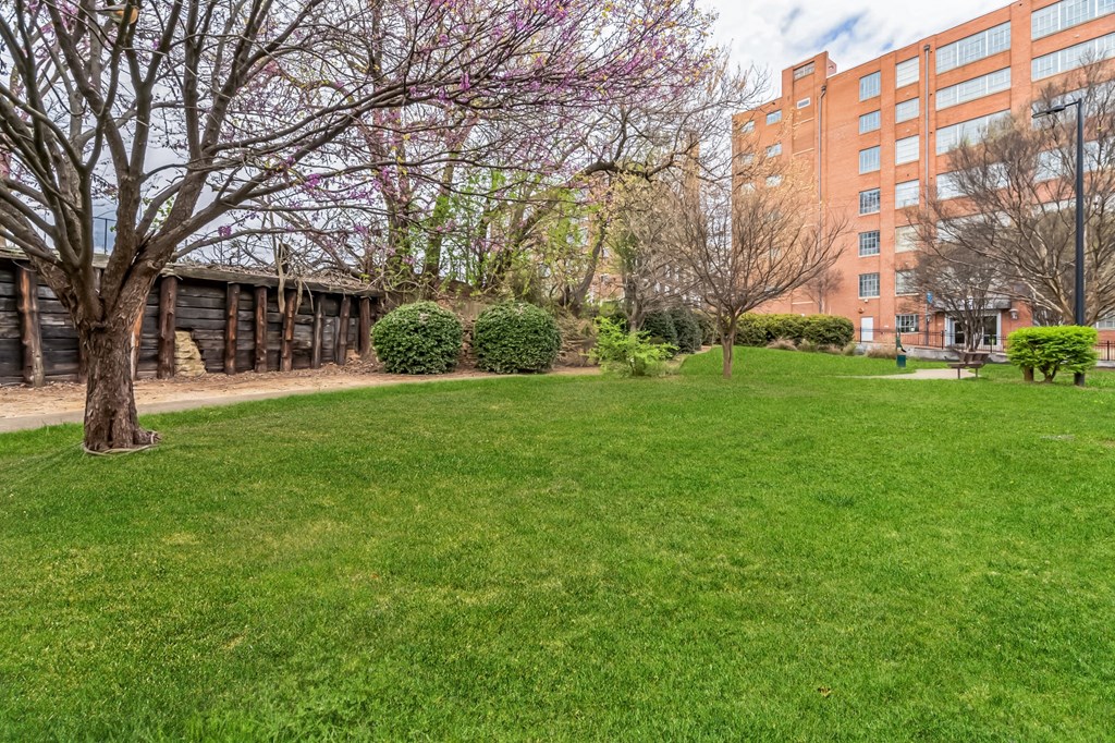 a park with grass and trees in front of a building