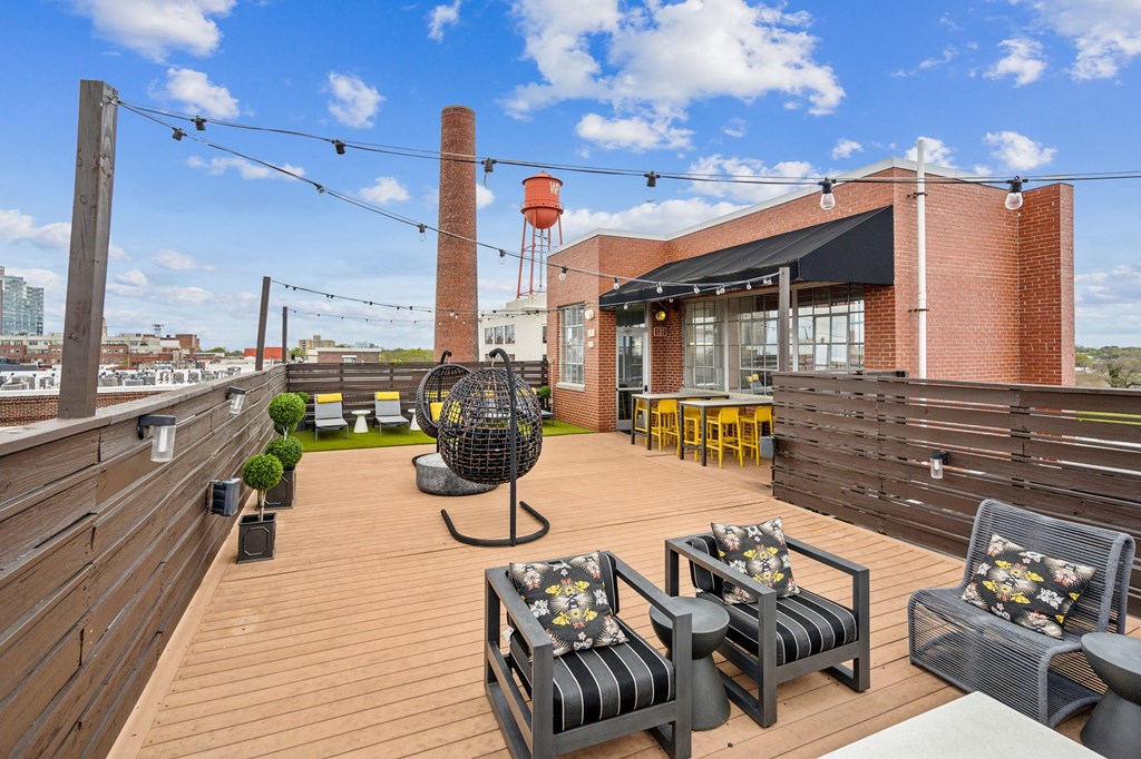 the deck on the top of a building with chairs and tables