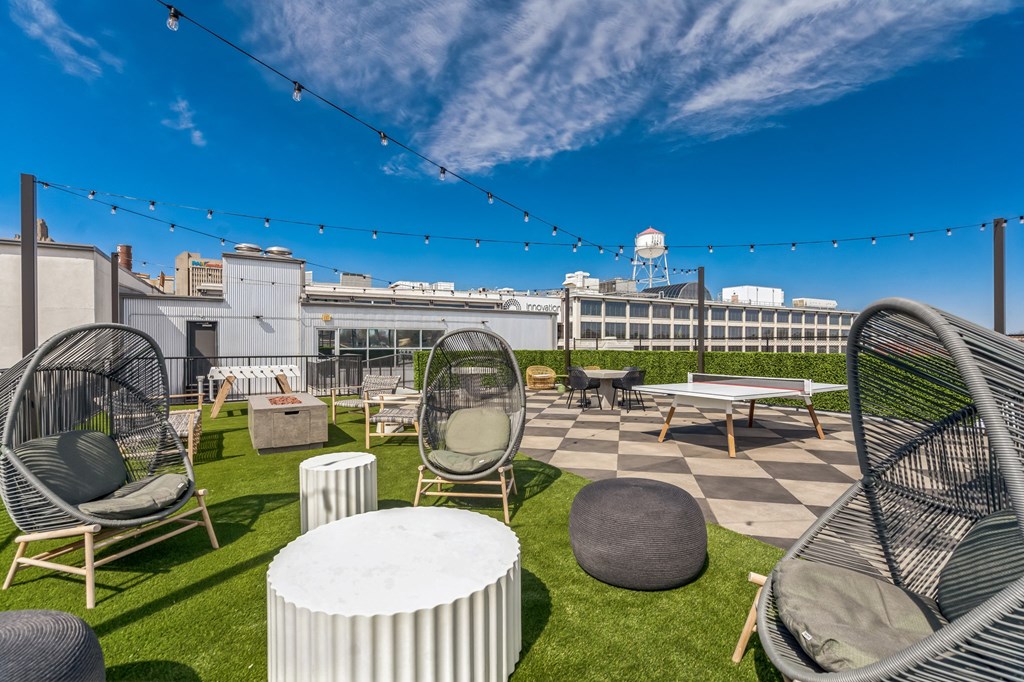 a roof top patio with chairs and tables and a building in the background