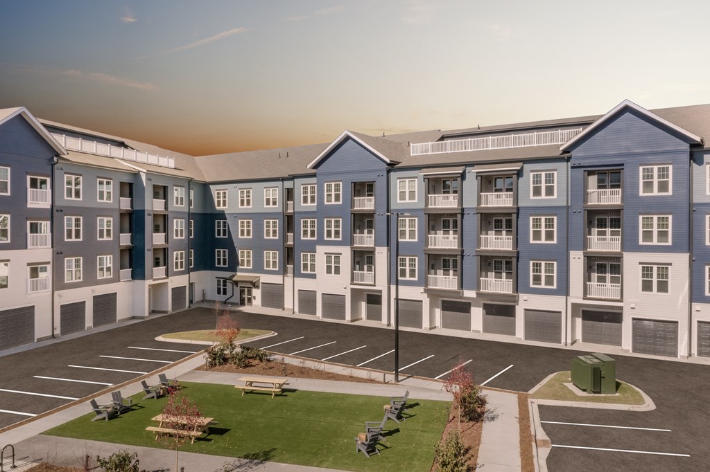 an aerial view of an apartment complex with a parking lot and grass