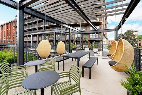A patio with tables and chairs and hanging chairs.