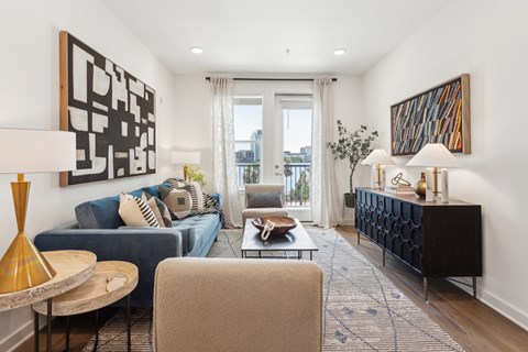A living room with a blue couch and a large abstract painting on the wall.