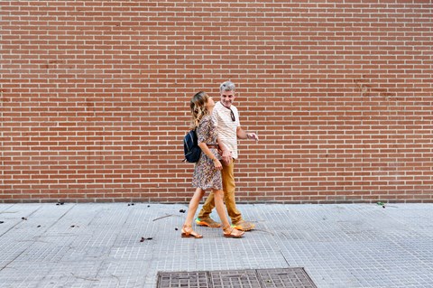 Two people walking on a brick wall.