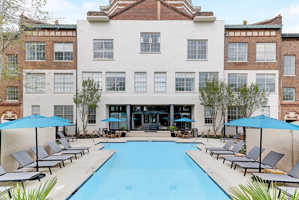 a white brick building with a large blue pool in front of it