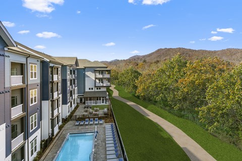 an aerial view of an apartment building with a pool and green lawn