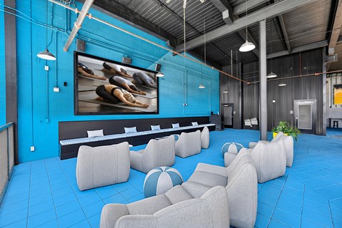 A room with blue walls and a large screen displaying a yoga class.