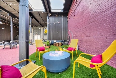 A brightly colored outdoor seating area with yellow chairs and a blue table.