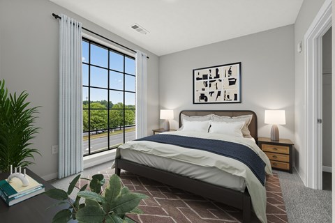 A bedroom with a large bed and a view of the outdoors through the window.