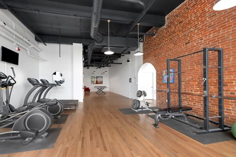 a gym with brick walls and wood floors and workout equipment