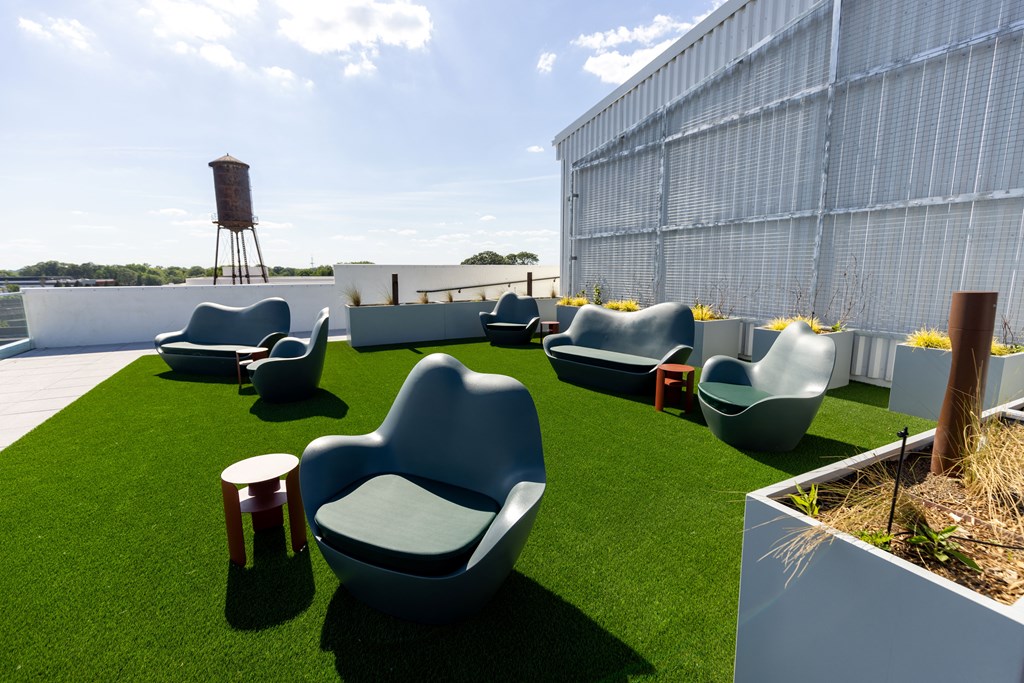 a roof garden with chairs and grass on a sunny day