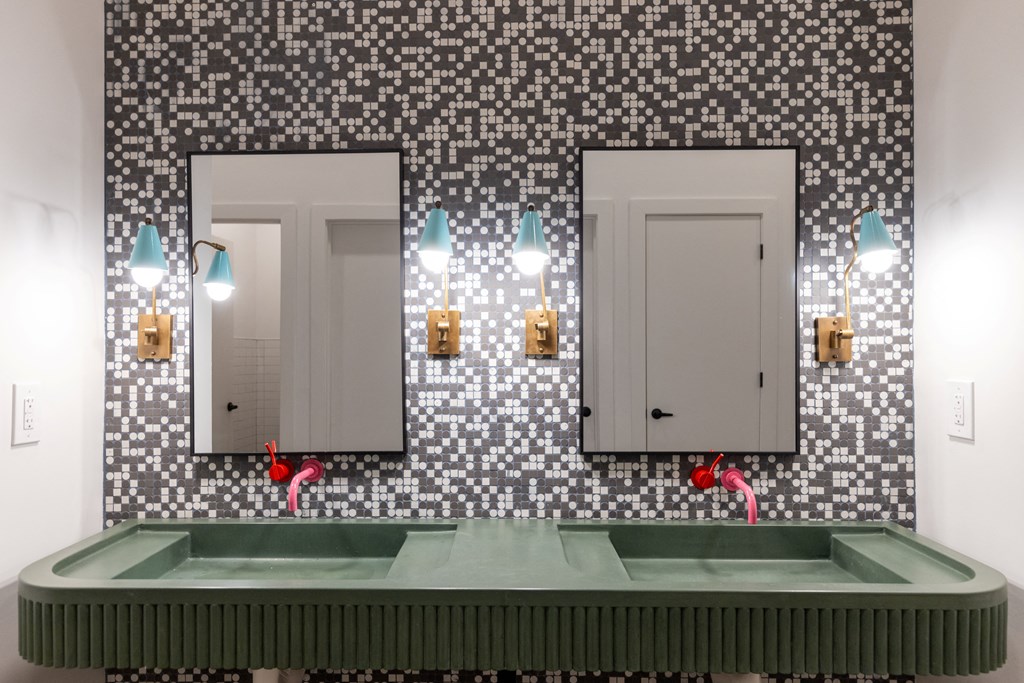 a bathroom with two sinks and two mirrors on a mosaic wall