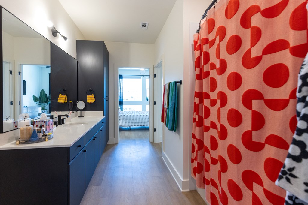 a bathroom with blue cabinets and a red and white shower curtain