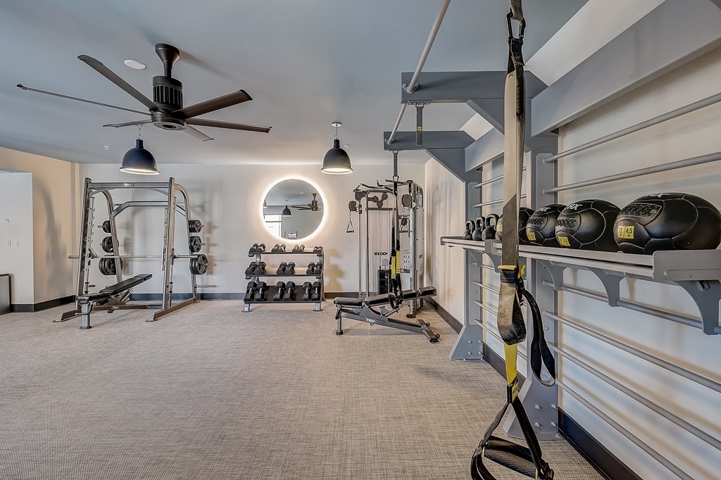 a home gym with weights machines and a circular mirror
