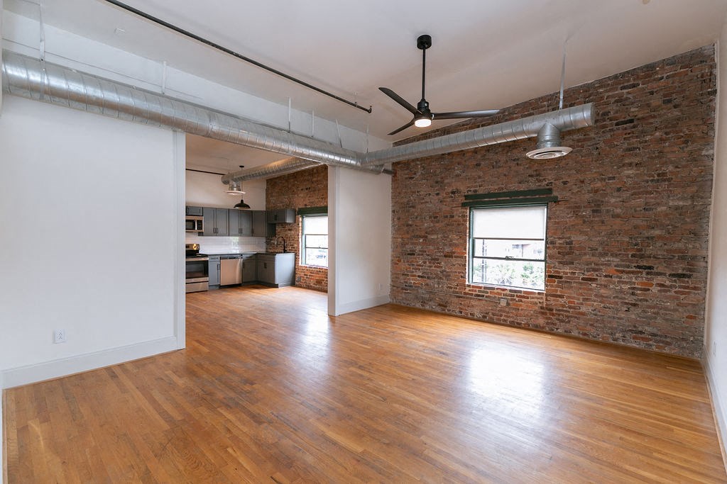 an empty living room with a brick wall and wood floors