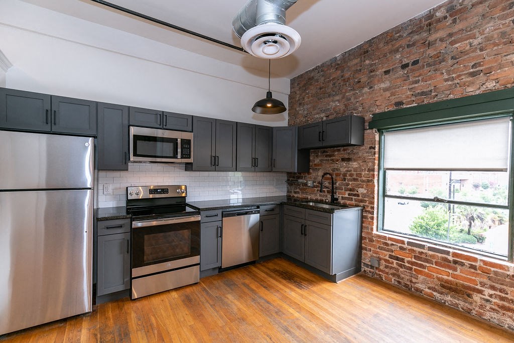 a kitchen with stainless steel appliances and a brick wall