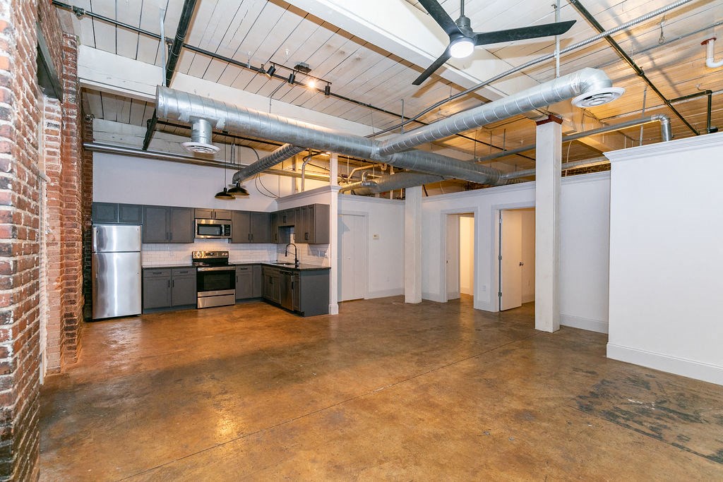 a large room with a kitchen and a exposed brick wall
