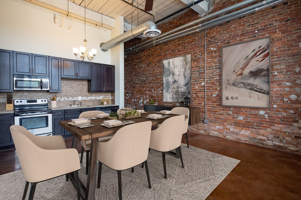 a dining area with a wooden table and chairs and a kitchen in the background