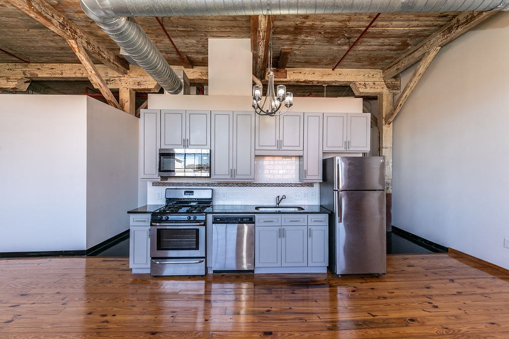 an empty kitchen with white cabinets and stainless steel appliances