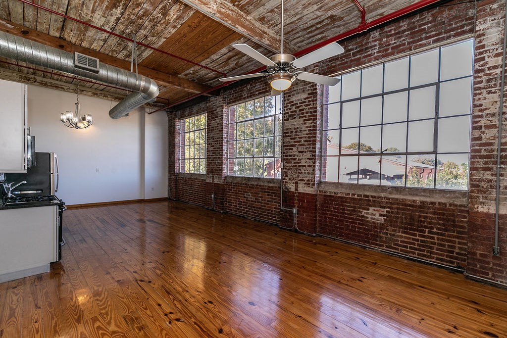 an empty room with exposed brick and a ceiling fan