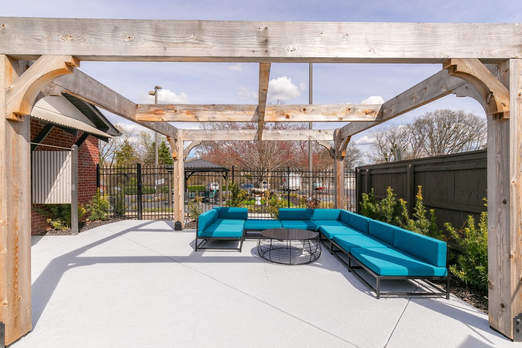 a covered patio with blue couches and a table