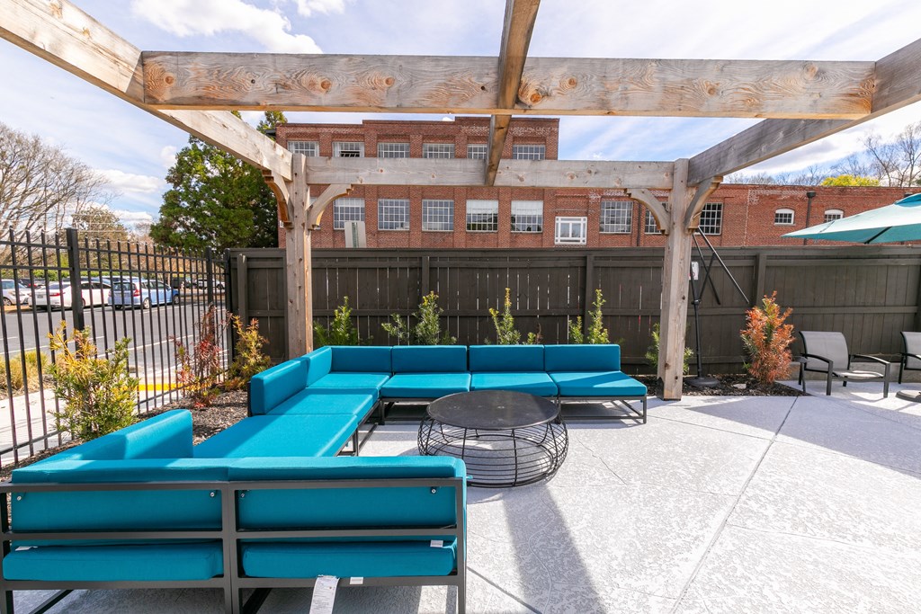 a patio with blue couches and a table and a pergola