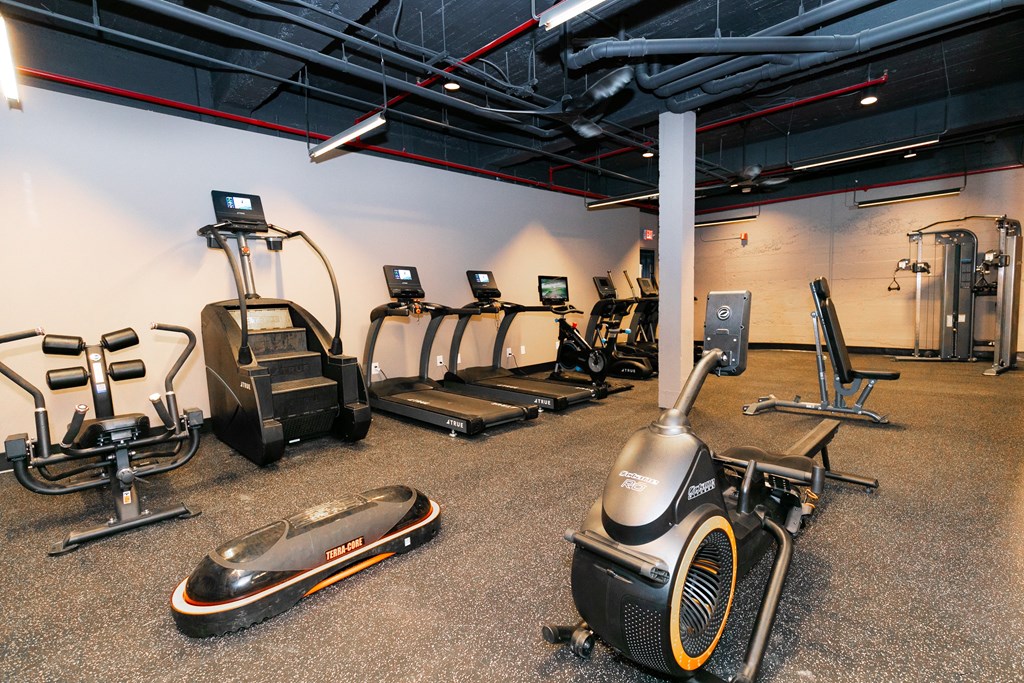 a gym with cardio equipment and weights on the floor