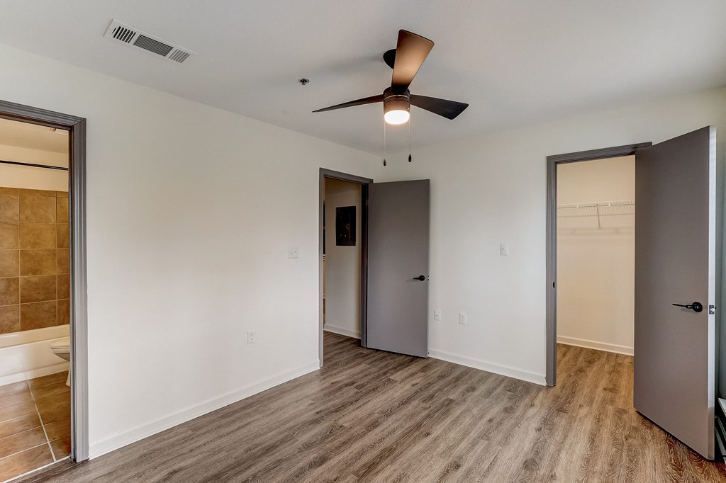 a bedroom with white walls and a ceiling fan