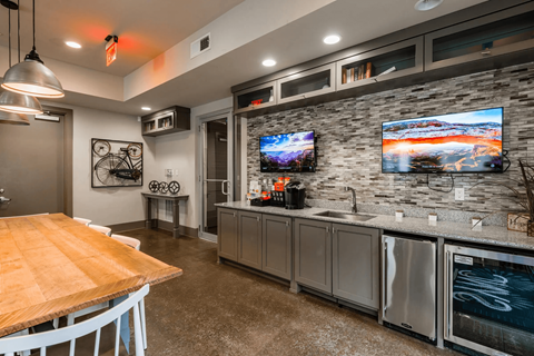 A modern kitchen with a wooden table and a stone backsplash.