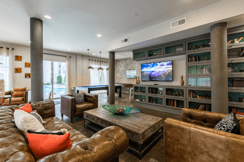 A living room with a brown leather couch and a flat screen TV mounted on the wall.