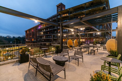a rooftop patio with tables and chairs and a building in the background