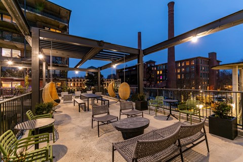 a rooftop patio with tables and chairs at night
