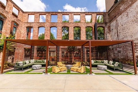 an outdoor area with couches and chairs under a wooden canopy
