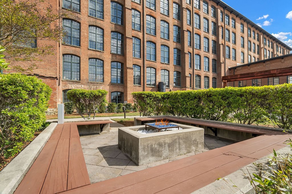 a courtyard with benches and a fire pit in front of a building