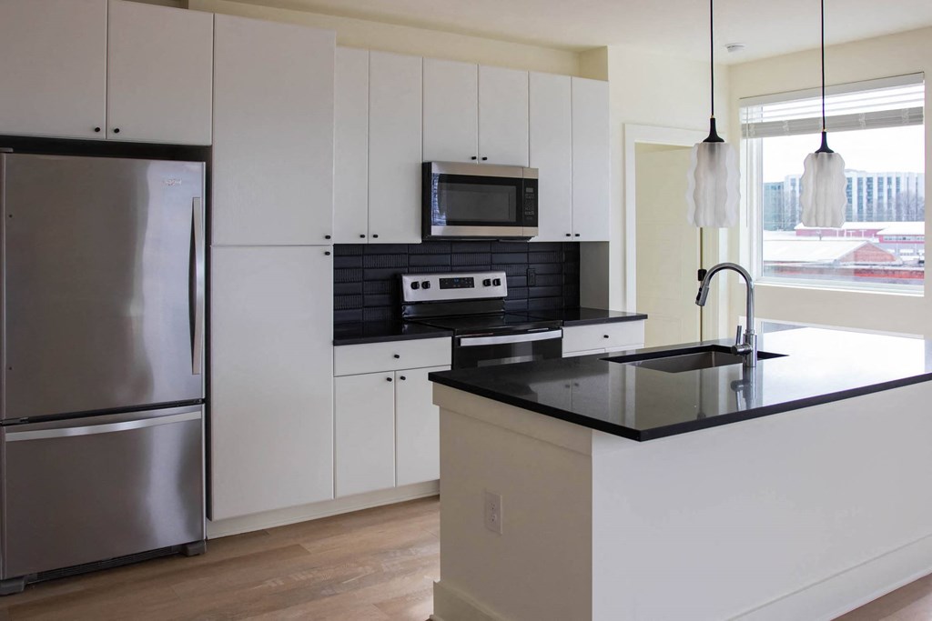 a kitchen with a black counter top and a stainless steel refrigerator
