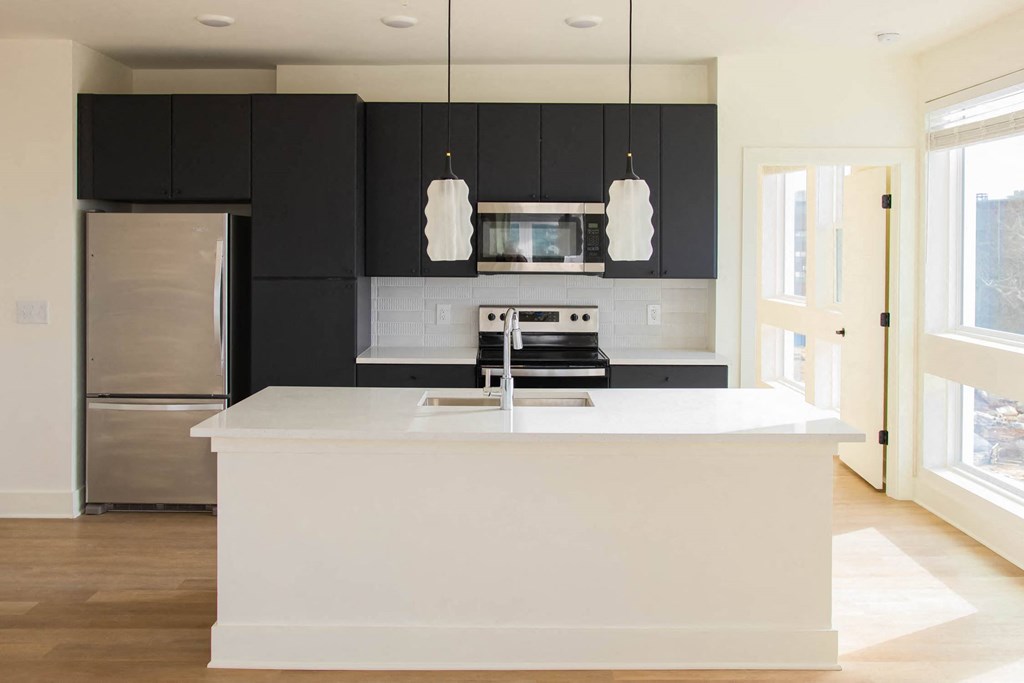 a white kitchen with black cabinets and a stainless steel refrigerator